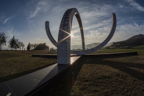 Immagine con monumento, nuvole, alberi, archi, sole, controluce, cielo, arco, raggi, prato, verde, azzurro, colline, ombre, ombra