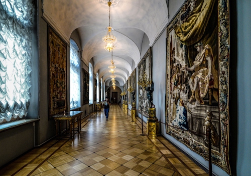 Immagine con lampadari, tende, finestre, corridoio, arazzi, galleria, persona, statue, pavimento, tavolini, museo, archi, parquet, piastrelle, vetrate, luce, luci, tavolo, legno