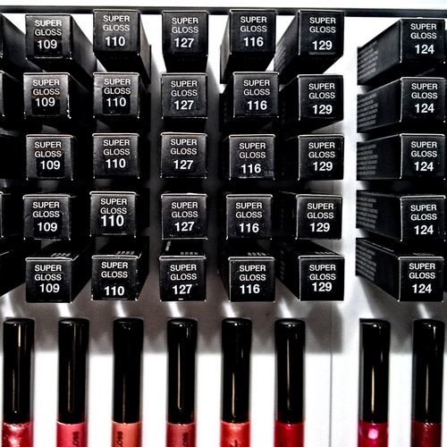 Immagine con numeri, nero, rosso, bianco, colori, rossetti, rossetto, scritte, quadrati, smalti, confezioni, scatole, espositore