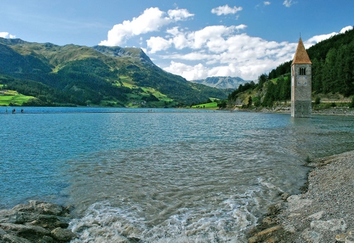 Immagine con campanile, nuvole, lago, acqua, verde, cielo, azzurro, alberi, montagne, colline, montagna, bianco, sommerso, panorama