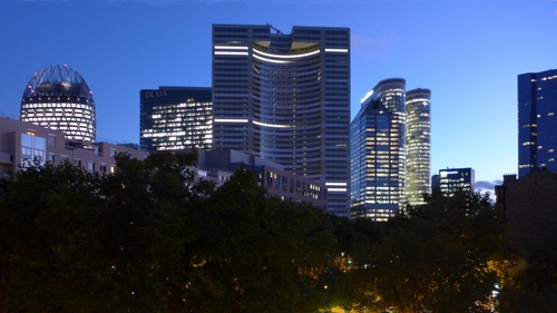 Immagine con grattacieli, luci, alberi, sera, cielo, finestre, palazzi, verde, azzurro, città