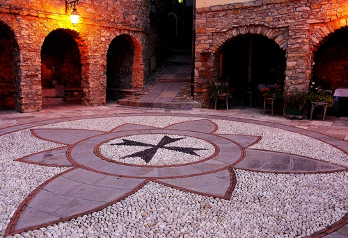 Immagine con croce, archi, piazza, lampione, sassi, sedie, vicolo, notte, stemma, luci, fiore, portici, cerchio, venti, portico, pietre, colonne, rosa, luce