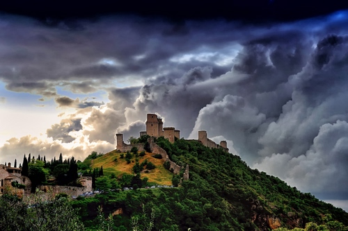 Immagine con castello, nuvole, alberi, collina, panorama, cielo, temporale, montagna, rocca, verde, torri