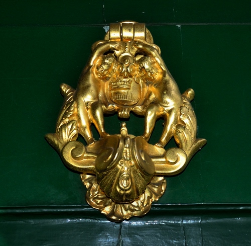 Immagine con oro, verde, batacchio, porta, stemma, metallo, giallo, legno, putti, battiporta