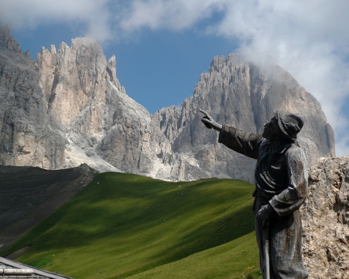 Immagine con statua, nuvole, cielo, montagne, prato, verde, montagna, cime, roccia, azzurro, rocce, dolomiti, erba, cappello, monumento, monti, mano