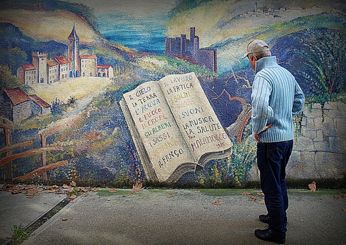 Immagine con libro, uomo, murales, passante, disegno, cappello, leggere