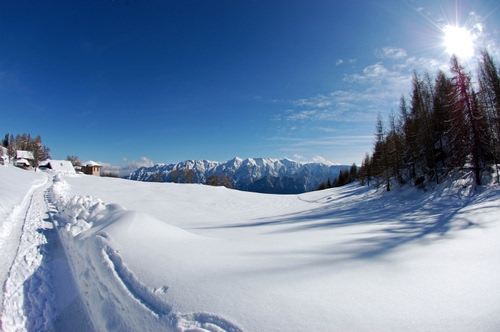 Immagine con neve, alberi, cielo, case, bianco, montagne, sole, montagna, inverno, ombra, azzurro, cime, panorama, paesaggio, strada, monti