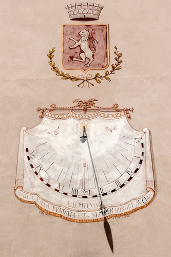 Immagine con meridiana, stemma, leone, ombra, numeri, ore, orologio, tempo, corona, muro