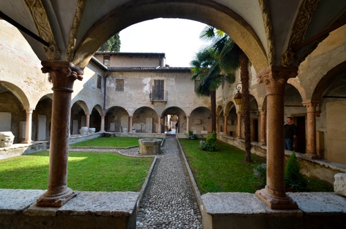 Immagine con pozzo, colonne, archi, chiostro, verde, prato, alberi, sentiero, porticato, portici, arco, finestra, portico, cortile, erba, palme