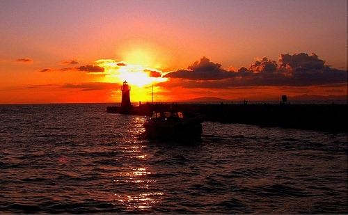 Immagine con tramonto, faro, mare, barca, nuvole, rosso, sole