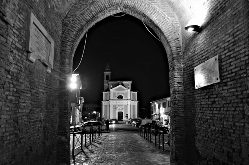 Immagine con chiesa, arco, bianconero, notturno, notte, lapidi, strada, portico, luci, campanile
