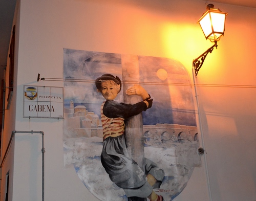 Immagine con lampione, murales, luce, murale, palo, fili, insegna, muro