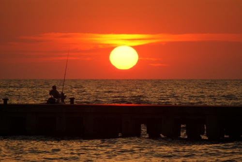 Immagine con pescatore, tramonto, mare, sole, rosso, acqua, canna, giallo, molo