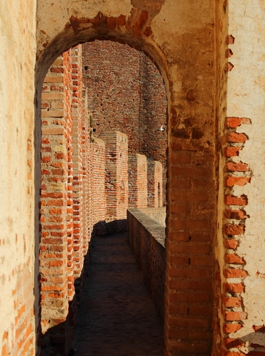 Immagine con arco, mattoni, castello, ombra, muro, porta, merli, passaggio, mura, parapetto, colonne