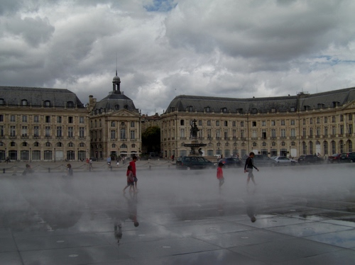 Immagine con nuvole, piazza, palazzi, persone, passanti, acqua, nebbia, pioggia, riflessi, fontana, riflesso