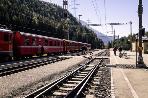 Immagine con treno, stazione, binari, biciclette, vagoni, alberi, ferrovia, persone, cielo, fili, rosso, bici, rotaie, montagna, pali