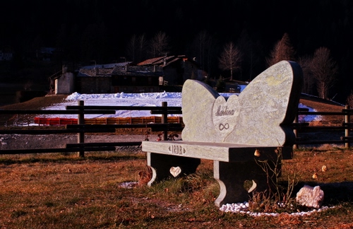 Immagine con panchina, staccionata, neve, case, pietra, marmo, scritta, iscrizione