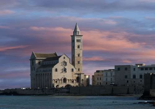 Immagine con chiesa, campanile, mare, nuvole, cielo, tramonto, case, acqua, borgo, rosone, scorcio, alba
