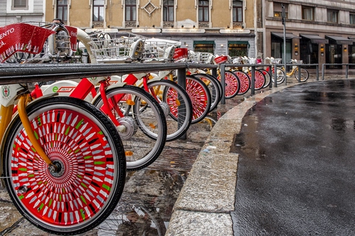 Immagine con biciclette, ruote, rosso, strada, finestre, parcheggio, bagnato, riflesso
