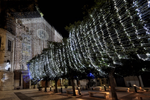 Immagine con alberi, chiesa, panchine, luci, luminarie, piazza, croce, notturno, strada, rosone, natale, addobbi