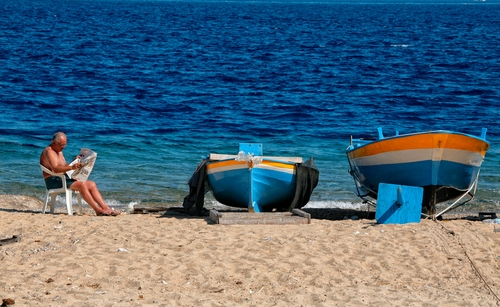 Immagine con barche, sabbia, mare, spiaggia, sedia, uomo, blu, acqua, giornale, azzurro, due, leggere, arancione