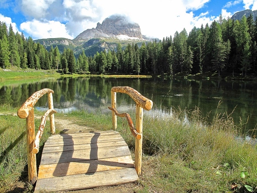 Immagine con lago, montagna, ponte, alberi, nuvole, legno, prato