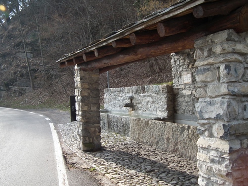 Immagine con lavatoio, strada, alberi, sassi, pietra, acqua, tetto, pilastri, colonne, legno, fontana