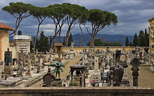 Immagine con cimitero, tombe, alberi, statue, pini, lapidi, montagne, croci, nuvole