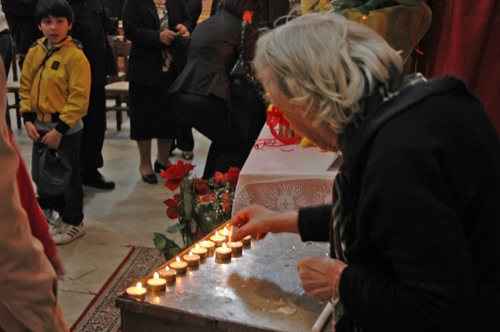 Immagine con bambino, lumini, fiori, chiesa, devozione, anziana, giallo, persone, donna, candele, rosso, ceri, fiamma, nero, luci, capelli, anziano, tappeto, accesi