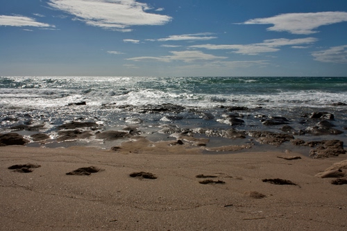 Immagine con mare, orme, sabbia, spiaggia, onde, cielo, nuvole, scogli