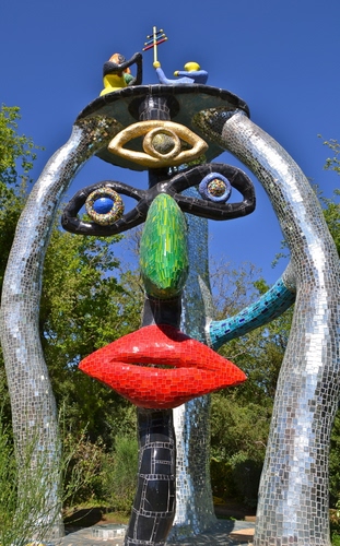 Immagine con verde, occhi, rosso, scultura, naso, bocca, azzurro, labbra, faccia, cielo, piante, nero, giardino, tarocchi, alberi, mosaico, viso