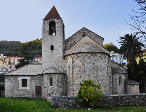 Immagine con chiesa, campanile, alberi, cielo, verde, prato, case, borgo, campana, abside, palma, azzurro