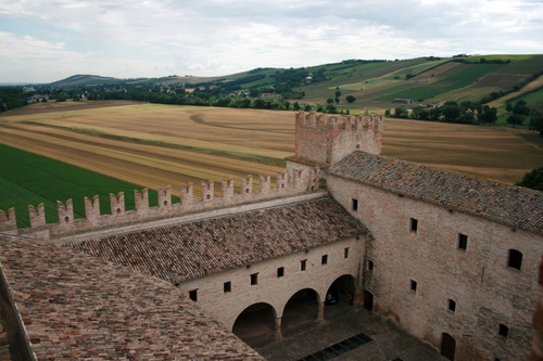 Immagine con castello, torre, merli, campagna, campi, colline, archi, tetti, portico