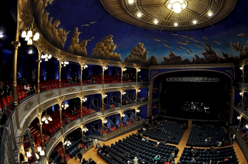 Immagine con palchi, teatro, poltrone, luci, platea, palcoscenico, soffitto, volta, nero, rosso, lampade, persone, scena, colonne, galleria, pubblico, nuvole, interno, lampadario, blu, lampioni, spettatori