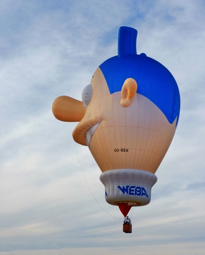 Immagine con mongolfiera, cielo, naso, nuvole, blu, pupazzo, pallone, volare, volo, bocca, cesto, denti, capelli, faccia, azzurro, cestino, scritta, orecchio