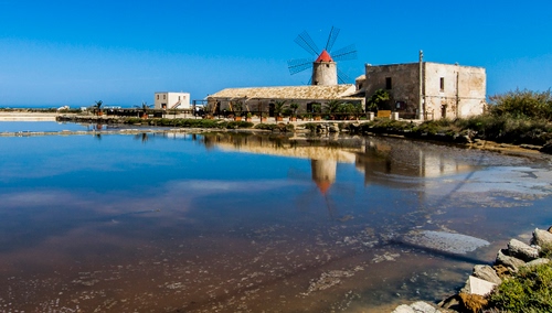Immagine con mulino, mare, acqua, riflesso, salina, pale, cielo, riflessi, azzurro