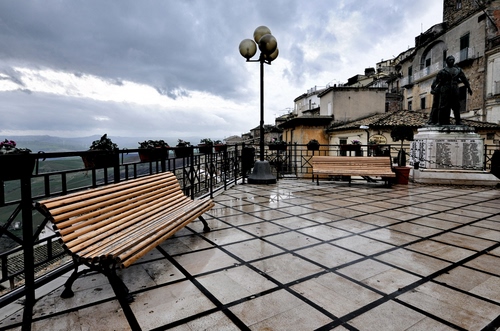 Immagine con lampione, panchina, pioggia, panchine, nuvole, statua, bagnato, monumento, piazza