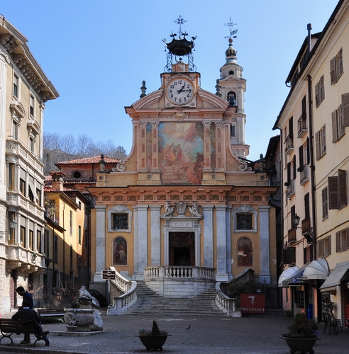 Immagine con chiesa, orologio, campanile, piazza, scalinata, affresco, fontana, croci, panchina, case, scale, balaustra, gradini, portone, finestre, palazzi, vasi