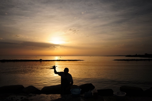 Immagine con mare, tramonto, controluce, uomo, cielo, pescatore, silhouette, alba, scogli, riflesso, sole, persona