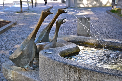 Immagine con fontana, acqua, oche, tre, zampilli, vasca, strada, spruzzi, terra, piazza, getti, zampillo, riflessi, scultura, statue