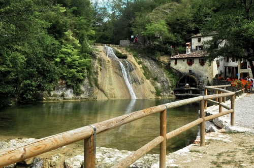 Immagine con mulino, cascata, acqua, alberi, ruota, verde, staccionata, casa, fiori, fiume, finestre, torrente, laghetto, steccato, legno, tetti, edificio