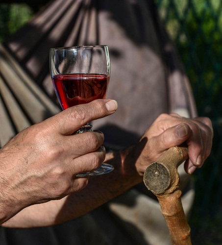 Immagine con bicchiere, bastone, vino, mani, rosso, ombre, legno