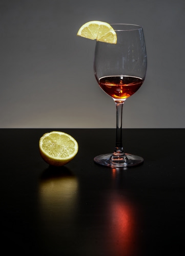 Immagine con bicchiere, limone, vetro, calice, riflessi, giallo, fetta, tavolo, rosso, nero, liquido, riflesso, stelo, vino