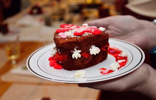 Immagine con piatto, dolce, cibo, torta, cioccolato, rosso, mani, marrone, fetta, cuori, zucchero, bianco