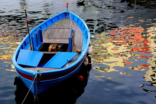 Immagine con barca, acqua, azzurro, riflessi, riflesso, legno, mare, rosso, colori, giallo, blu, motore, cima, bandiera, poppa, corda, lago