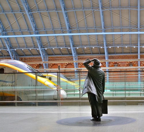 Immagine con stazione, uomo, cappello, treno, treni, statua, borsa