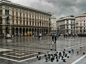 piazza, piccioni, pioggia, ombrelli, palazzi, nuvole, persone, portici, archi, finestre, lampioni, colonne, cielo, bagnato, città, colombi